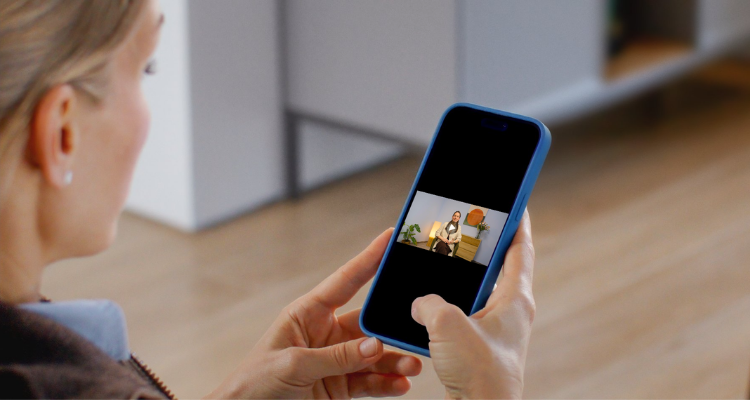 Frau schaut ein Lernvideo in der isi-App auf ihrem Smartphone