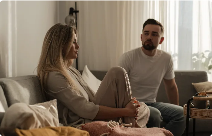 Partnerin und Partner sitzen bei PMS nachdenklich auf dem Sofa